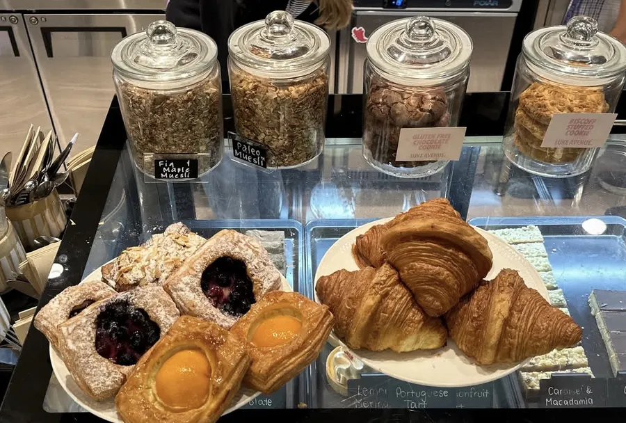 Bakery display case with muesli jars, cookie jars, croissants and fruit tarts