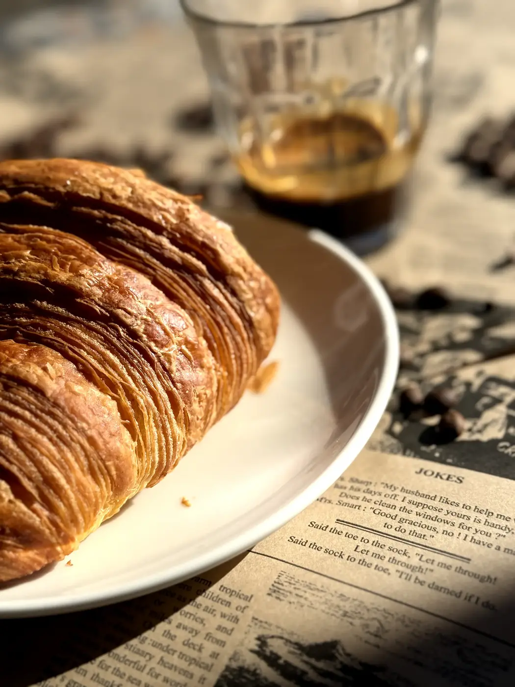 Croissant on a plate beside an espresso