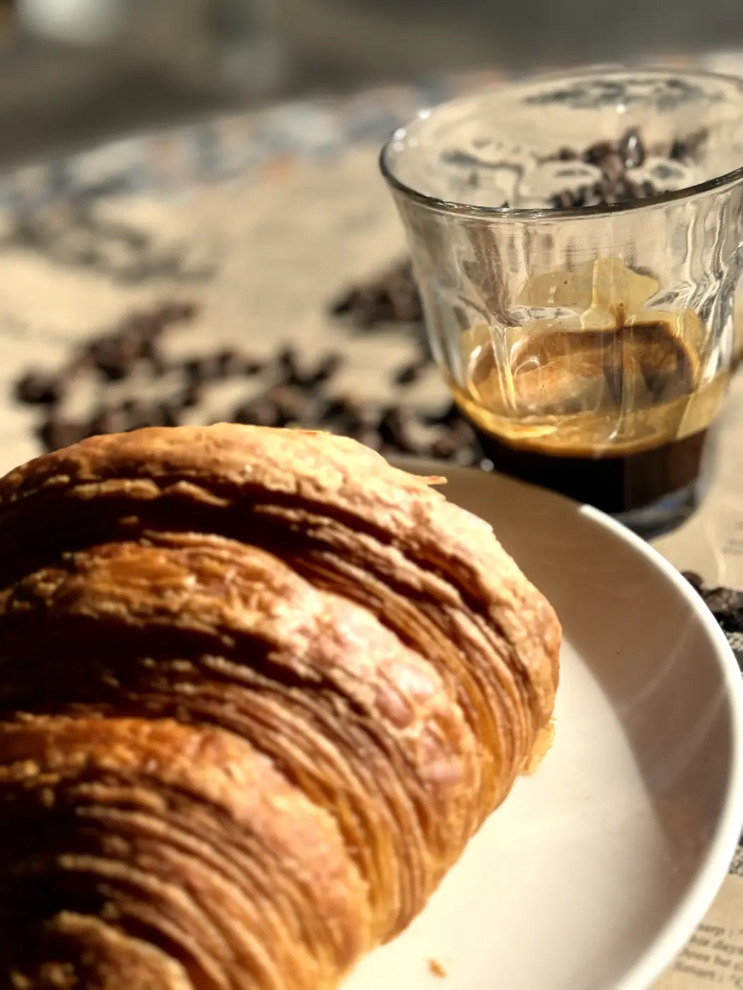 Flaky croissant beside an espresso