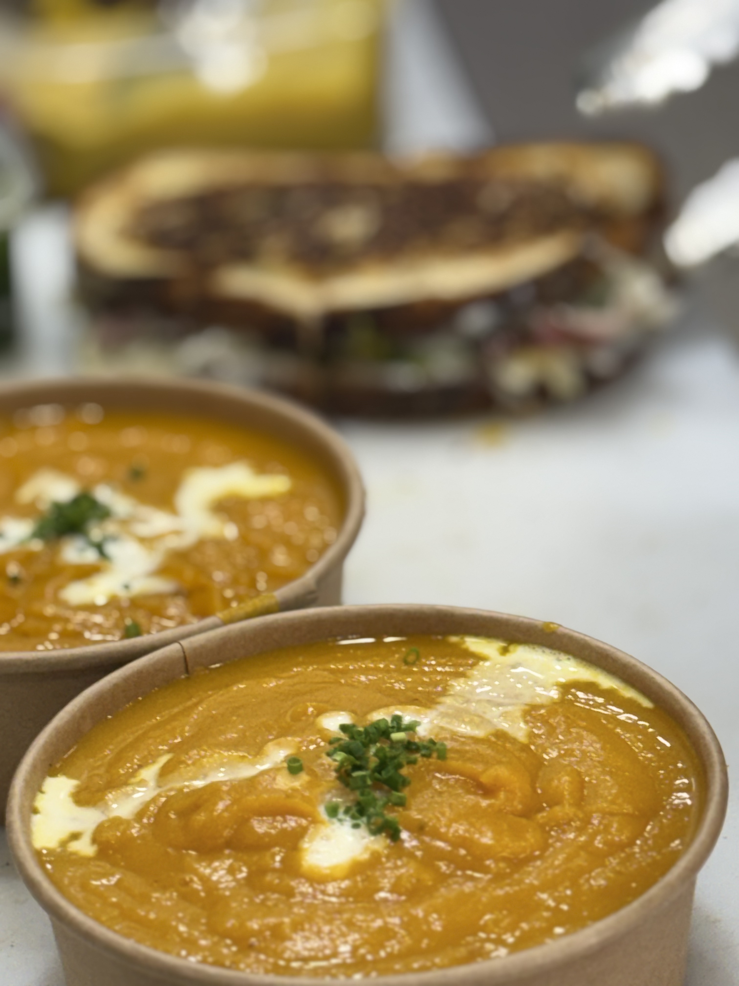 Bowls of pumpkin soup with a toastie in the background